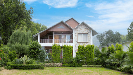 A charming villa with a white facade, surrounded by lush greenery and a manicured garden - Megha Resort & Villas, Dehradun