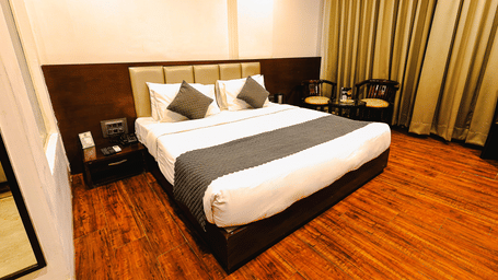 Bright guest room with plush king bed, warm interiors and floor-to-ceiling curtains at TGI Apple Inn, Ajmer Road, Jaipur.