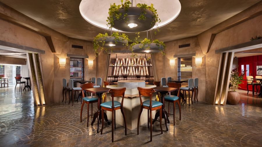 A bar area at Shilton International, Kochi, with a central round bar, stools, and hanging plant decorations.