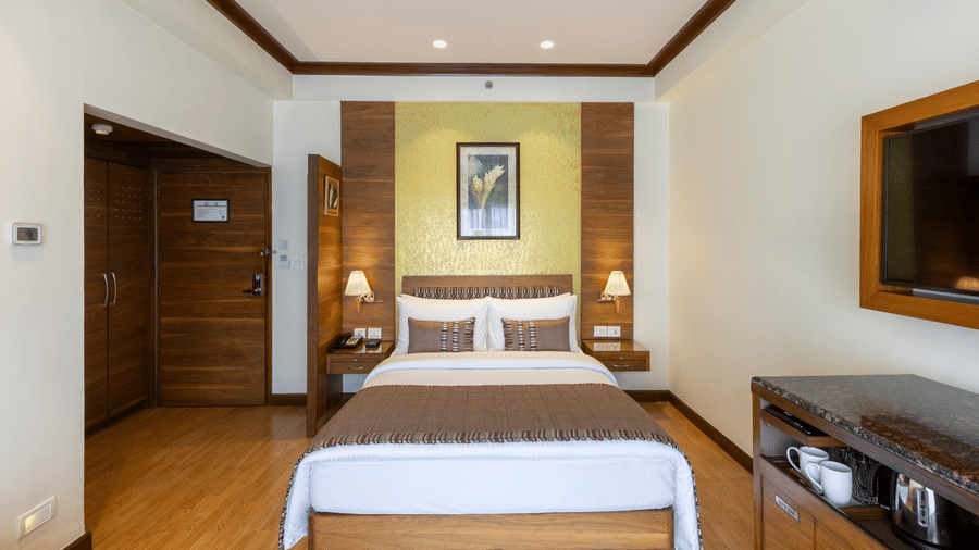 Business Club Room with a bed, framed artwork and wall mounted television at Kenilworth Hotel, Kolkata.