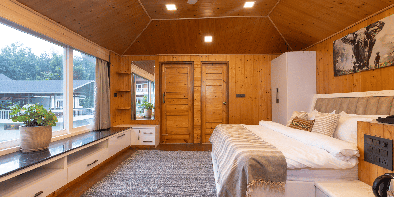 A spacious, all-wood interior room with two double beds and a large window bench overlooking the scenic outdoors - Megha Resort & Villas, Dehradun