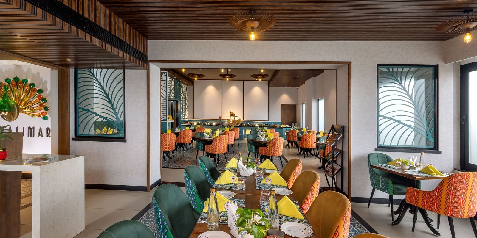 Dining space at Shalimar Restaurant in Zibe Luxe Hyderabad by GRT Hotels, adorned with colorful seating, ceiling lights, and artistic decor.