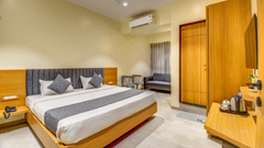 Executive Room at VITS Select Nashik Hotels & Resorts featuring a plush bed facing the TV on the wall under which a tea and coffee maker is placed on a wooden surface