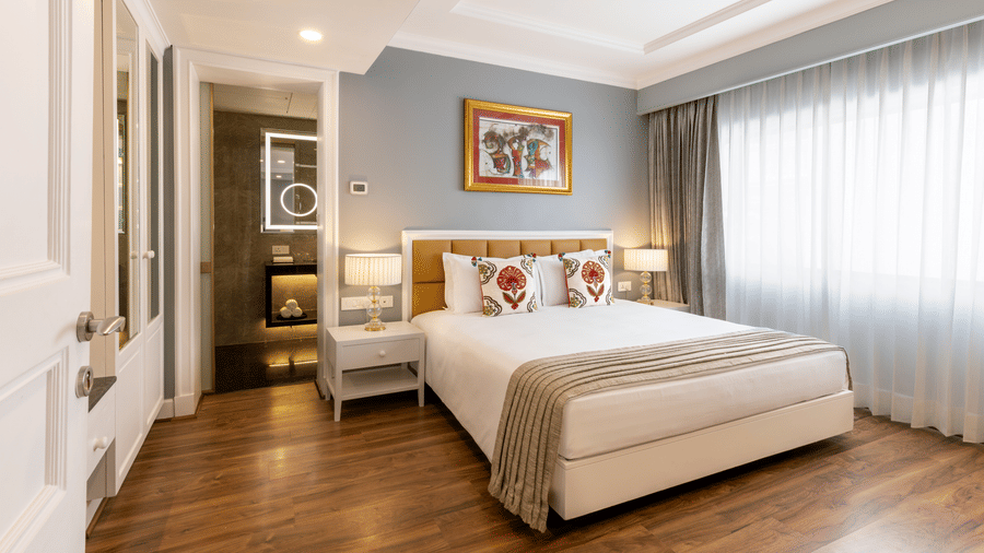 Junior Suite with a bed and framed artwork near the room entrance at Kenilworth Hotel, Kolkata.
