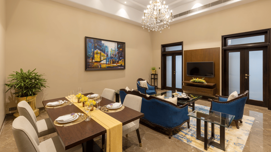 Presidential Suite with a dining table and lounge seating beneath a chandelier at Kenilworth Hotel, Kolkata.
