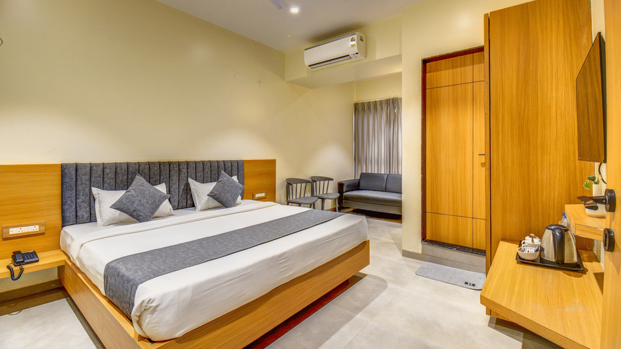 Executive Room at VITS Select Nashik Hotels & Resorts featuring a plush bed facing the TV on the wall under which a tea and coffee maker is placed on a wooden surface