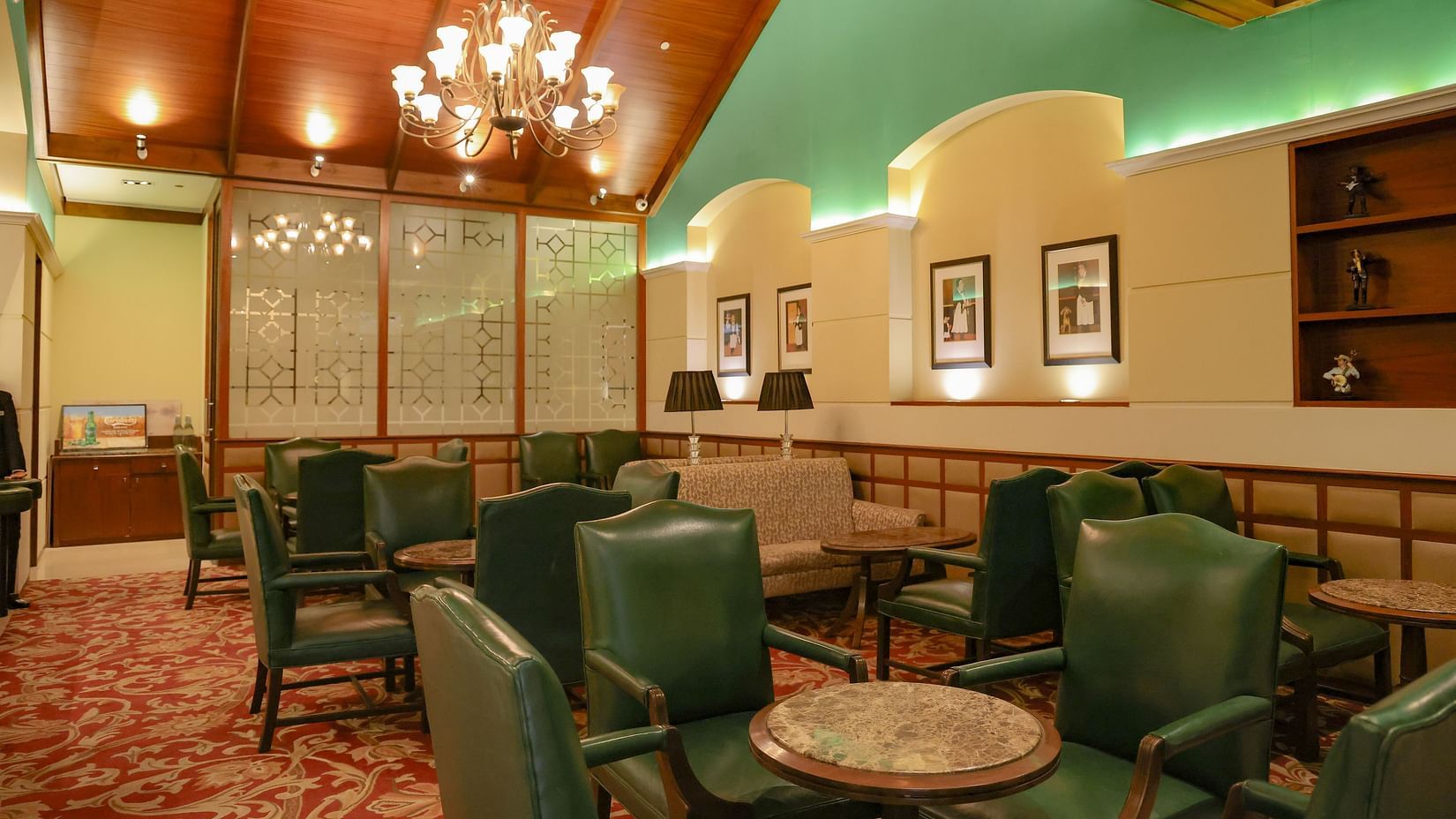 A stylish lounge with green leather chairs, a chandelier, and decorative elements - Balaji Sarovar Premiere, Solapur
