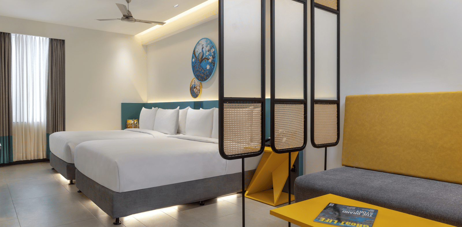 A neatly arranged room featuring 2 beds, a partition, a couch and a coffee table | Zibe Luxe Hyderabad by GRT Hotels 