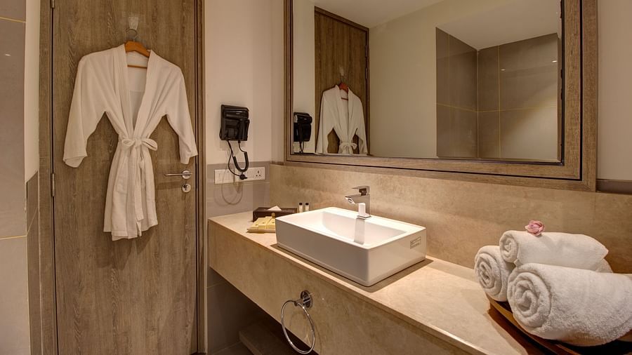 overview of the bathroom of with a bathrobe kept on a hanger at Rhythm Gurugram