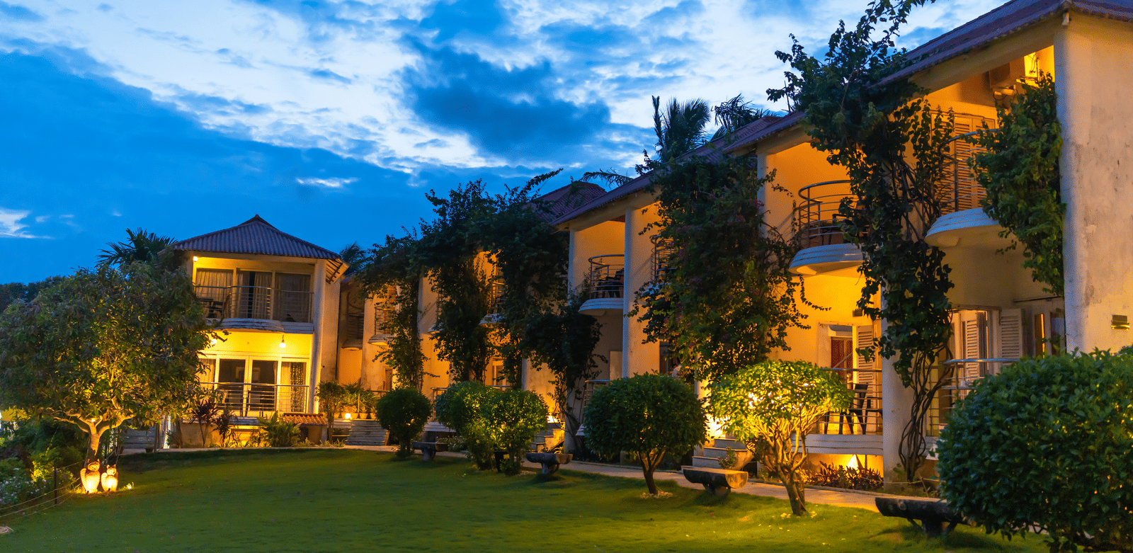 Two-storey hotel complex illuminated at dusk with ivy-covered walls and a green lawn - Hotel Seagull Digha