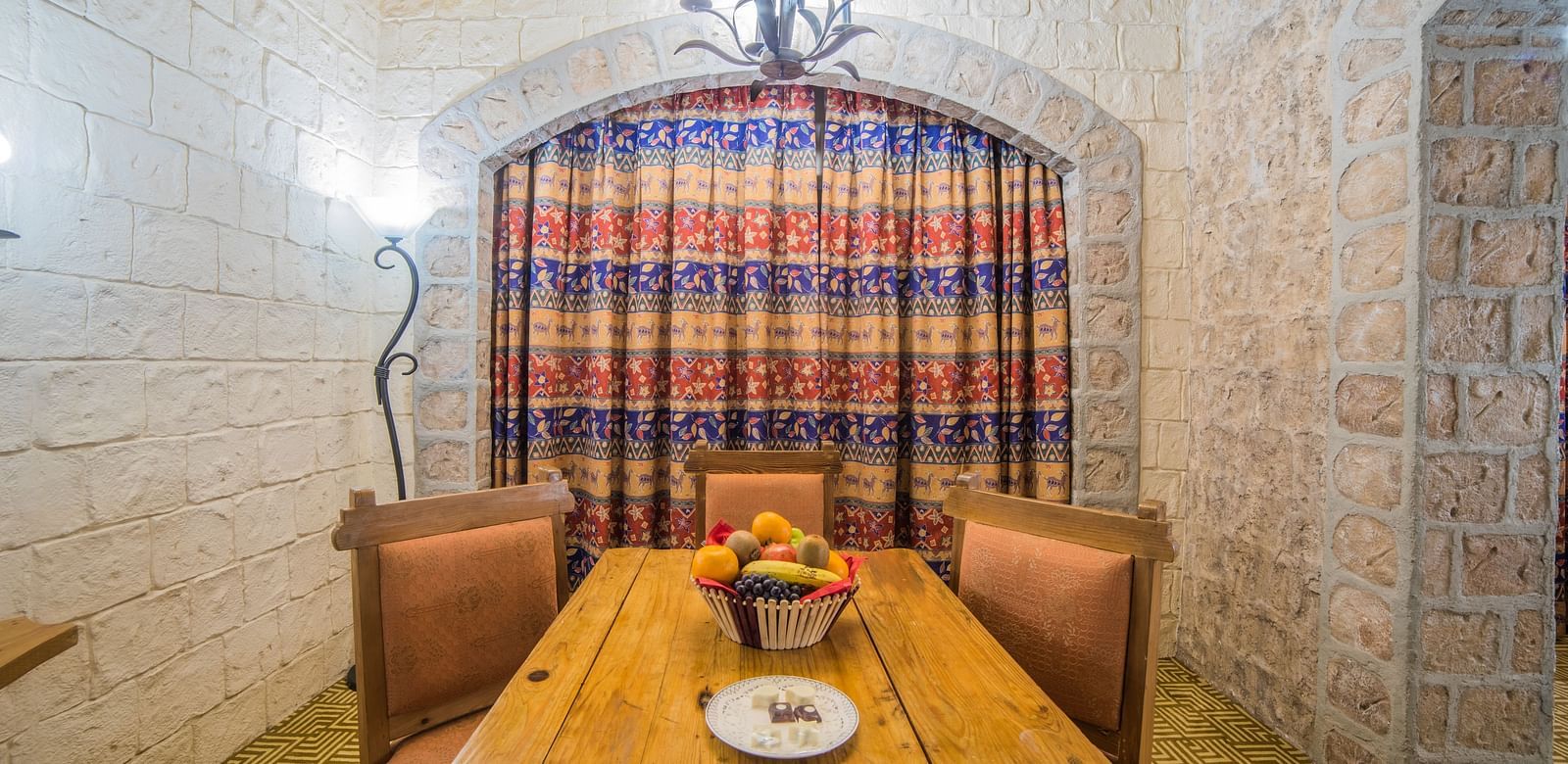 A dining area in a hotel room featuring a robust wooden table and chairs set against a backdrop of a large checkered curtain at  Sitara Luxury Hotel in Hyderabad near Ramoji Film City.