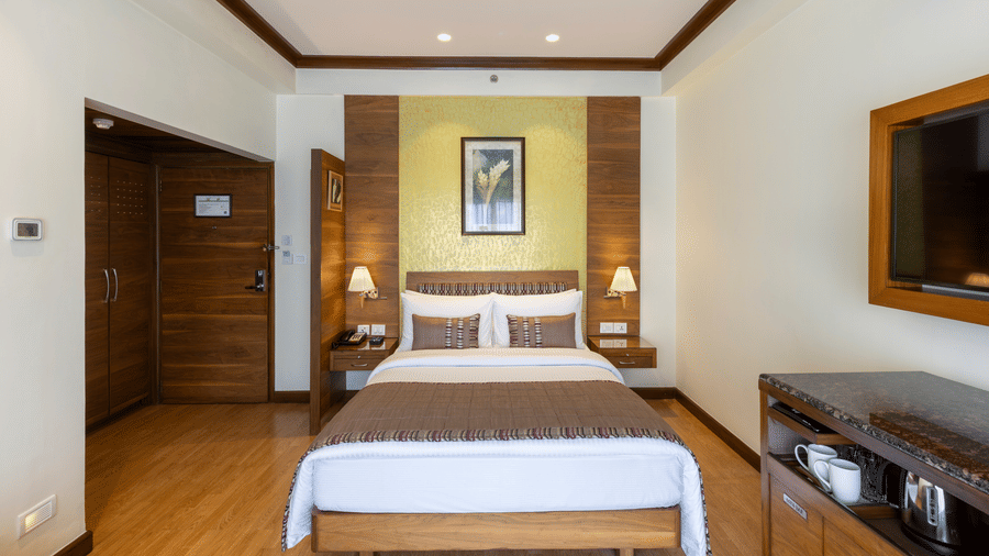 Business Club Room with a bed, framed artwork and wall mounted television at Kenilworth Hotel, Kolkata.