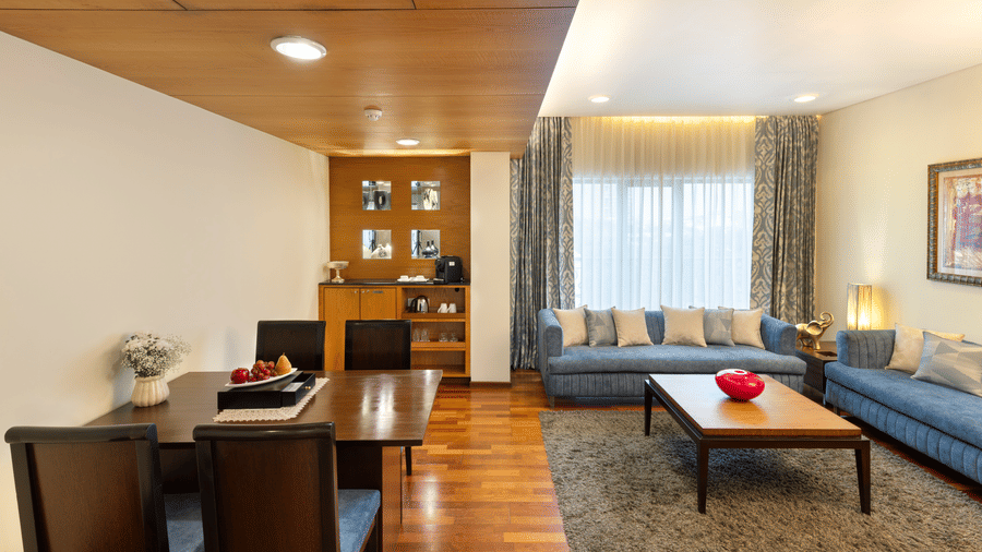 Russel Suite with a dining table and lounge seating in wood panelled interiors at Kenilworth Hotel, Kolkata.