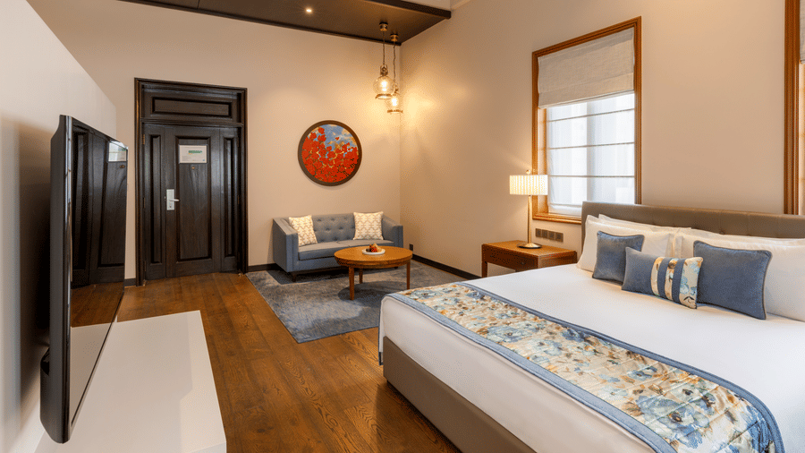 Premier Club Suite with a bed, seating area and wall mounted television at Kenilworth Hotel, Kolkata.