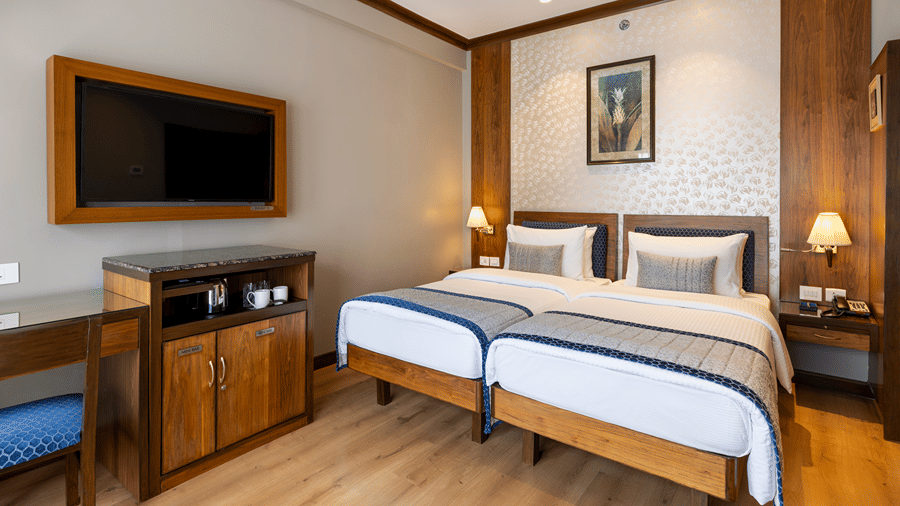 Executive Room with twin beds and a wall mounted television at Kenilworth Hotel, Kolkata.