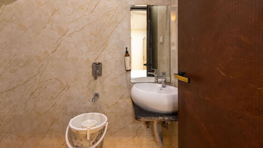 Bathroom with shower area, a mirror, and sink near a wooden door at Pravasa Stay Dewas Naka, Indore.