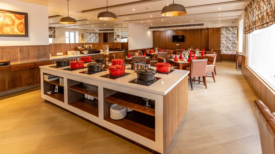 A buffet counter with dishes, containers, and seating arranged in a dining area at Indraprastha Resort & Spa, McLeod Ganj.