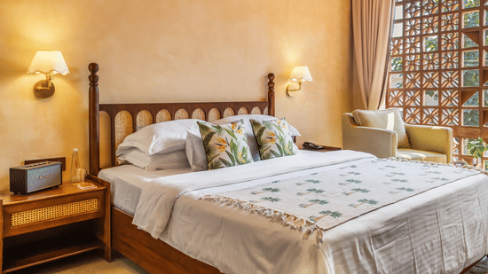 Bedroom at Unseen Boutique Hotel with lattice wooden panels, warm wall tones, bedside tables, and natural light through large windows.