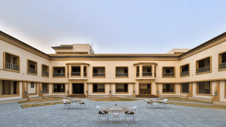 An open-air central courtyard with outdoor dining tables surrounded by the resort's multi-storey wings - Tathastu Chavri Resort, Jawai