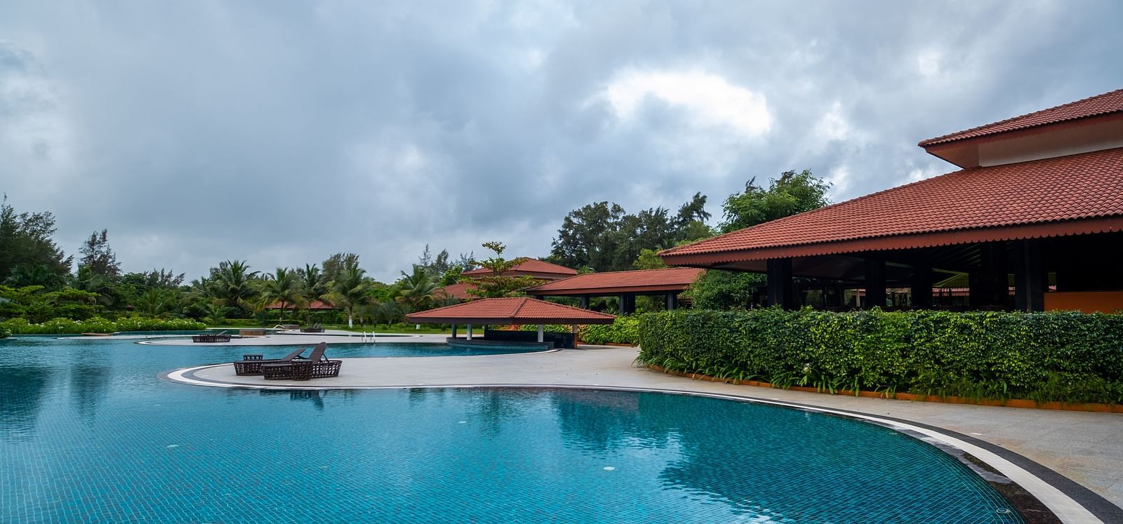 An overview of the swimming pool inside gamyam retreat with trees in the background