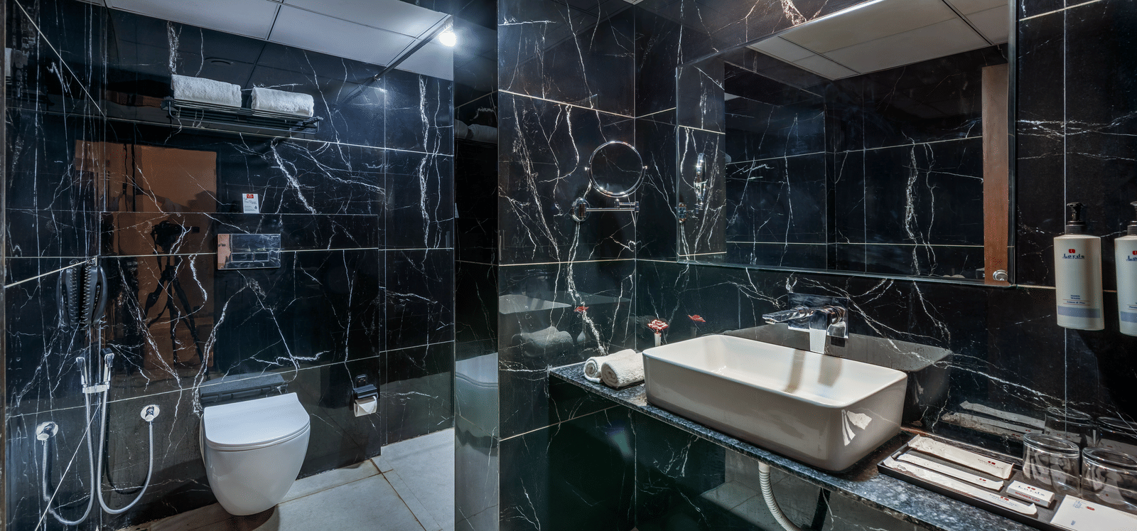 Modern bathroom with glass shower enclosure and sleek marble interiors at Lords Studio Inn, Jamnagar.