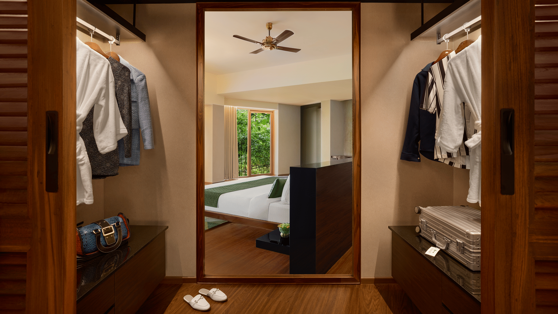 A walk-in wardrobe features clothes hanging on rails, shelves with items, and a mirror showing a reflection of a bedroom at Amanzi Resort.