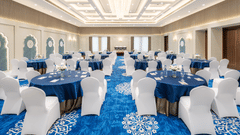 An image of Sangeet banquet hall, adorned with round tables and enhanced by elegant ambient lighting - MJ Sarovar Portico, Haridwar