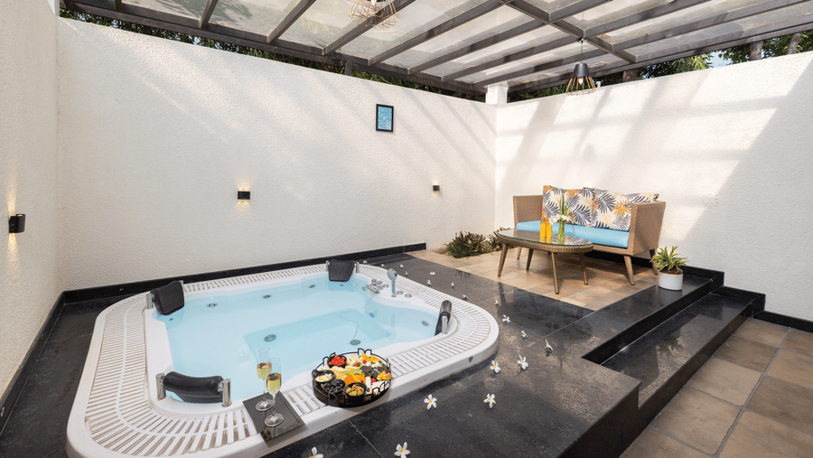 An indoor jacuzzi, set into the floor with towels and items placed on the edge under a covered ceiling.