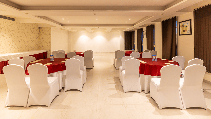 A banquet hall with tables, chairs, and lighting fixtures arranged for an event at Indraprastha Resort & Spa, McLeod Ganj.