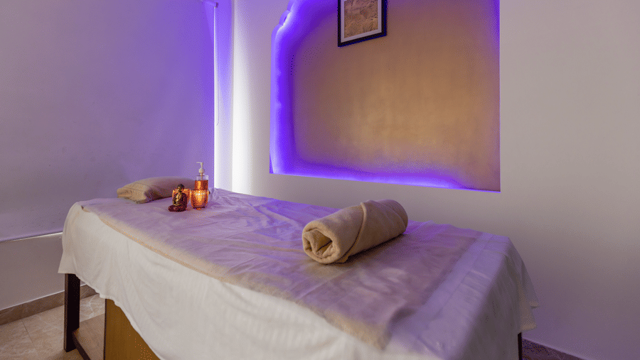 A spa room with a massage table, towels, and lighting setup inside at Indraprastha Resort & Spa, McLeod Ganj.
