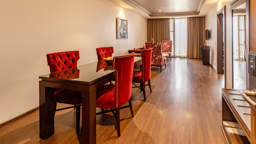 A room with a long table, multiple red chairs, seating area, and windows at Indraprastha Resort & Spa, McLeod Ganj.