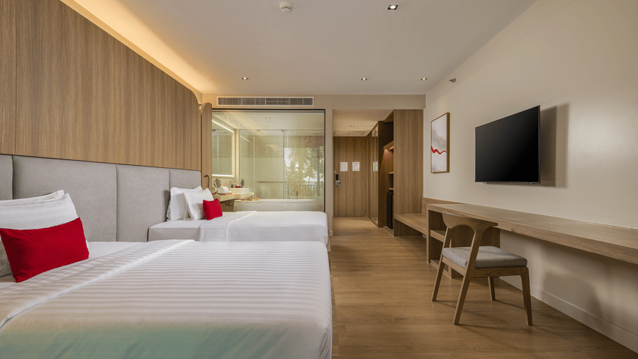 A view of a Jet Tub Twin bedroom showcasing 2 bed, work desk, wall-mounted television, and a passage leading to another area at Ramada Palace.