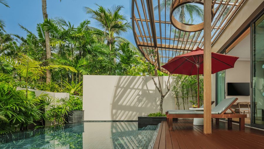 An outdoor poolside area of Private Pool Villa with seating, a pergola roof, and surrounding tropical greenery at Ramada Resort.