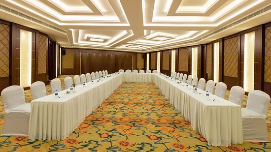 Elegant Jade Room with U-shaped table arrangement and chairs. The room features patterned carpet, wood-paneled walls, and bright, geometric ceiling lights