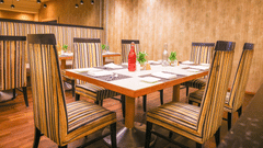A stylish restaurant interior featuring striped chairs, a wooden table, and ambient pendant lighting - Balaji Sarovar Premiere, Solapur