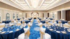 An image of our Sangeet banquet hall with large round tables and ambient lighting - MJ Sarovar Portico, Haridwar