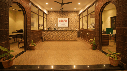 Interior view of the Adamo The Village reception area with a front desk, stone walls, and archways.