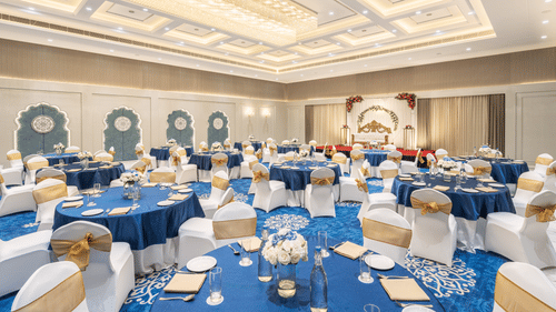 A view of our Sangeet banquet hall featuring spacious round tables and soft, ambient lighting for a warm atmosphere - MJ Sarovar Portico, Haridwar