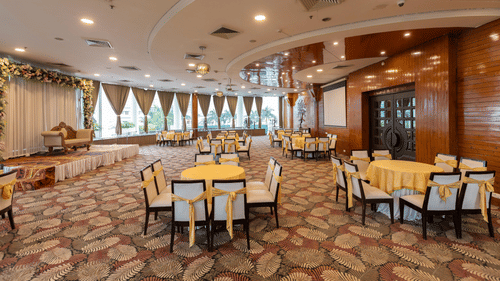  A large banquet hall or event space with multiple round tables set for a function - Pride Premier Dehradun