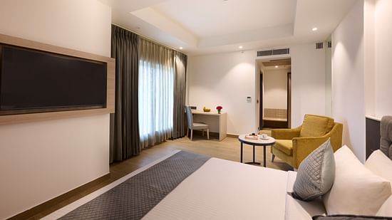 A hotel room with a large bed placed in front of a wall-mounted television