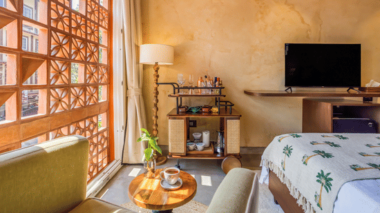 Bedroom at Unseen Boutique Hotel with patterned bedspread, wooden furniture, bedside lamps, and wall?mounted TV.