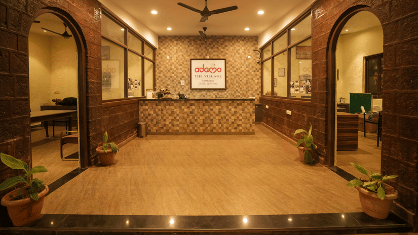 Interior view of the Adamo The Village reception area with a front desk, stone walls, and archways.