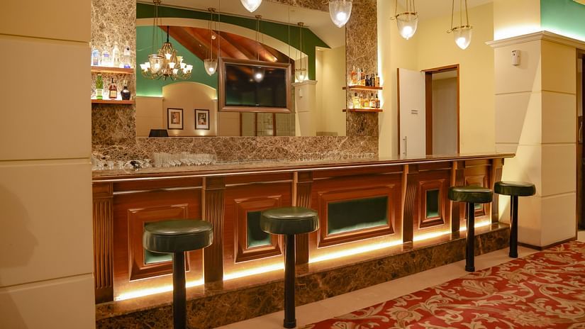  A well-lit bar area with a marble counter, bar stools, and a display of spirits - Balaji Sarovar Premiere, Solapur