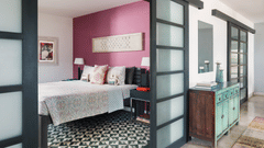 A bedroom at Owl and the Pussycat Hotel in Galle with a bed, patterned flooring, sliding glass doors, and an adjoining sitting area.