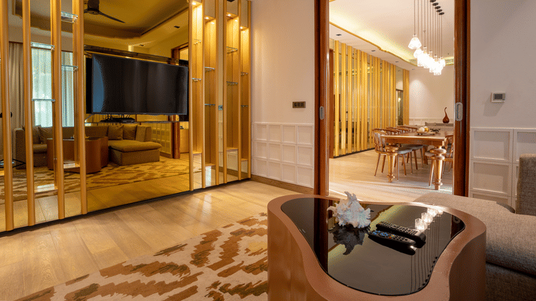 A stylishly decorated hotel room with a large bed and a prominent gold-toned, mirrored wall that reflects the room's elegant and contemporary design.