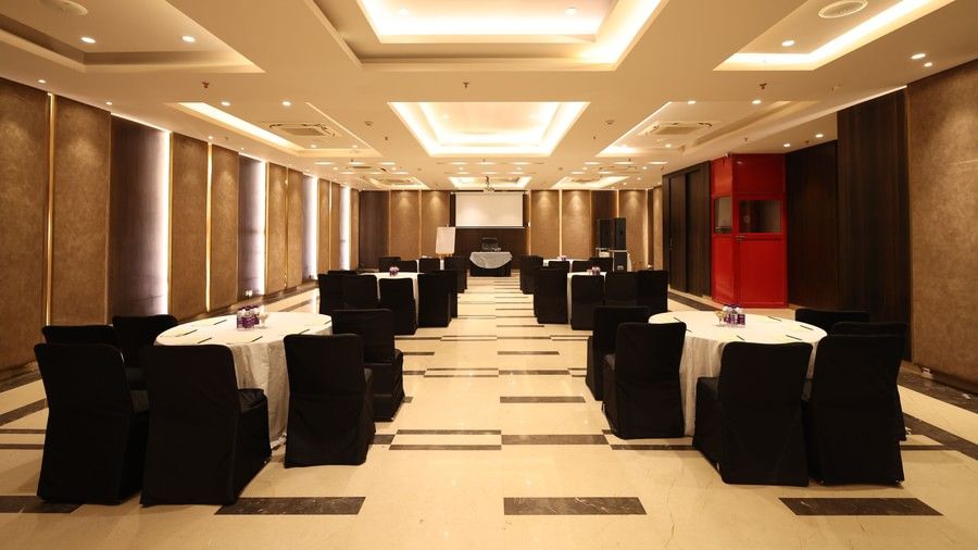 A large banquet or conference hall with multiple tables and chairs, elegantly decorated for an event.