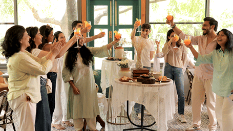 A group of people raising glasses together at Under The Neem during a celebration around a decorated dining table.