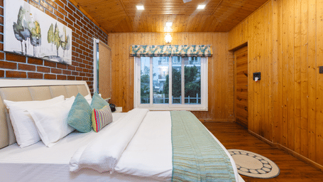 A comfortable, modern bedroom with wood-panelled walls, a large bed, and a simple, decor - Megha Resort & Villas, Dehradun