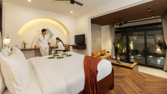 bedroom with a large bed featuring a person in a white robe, modern cabinetry, and sleek decor at The Golden Tusk, Jim Corbett