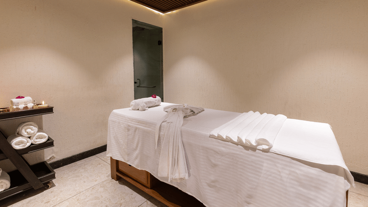 A single, dimly lit spa treatment room with one massage table at The Golden Tusk, Jim Corbett